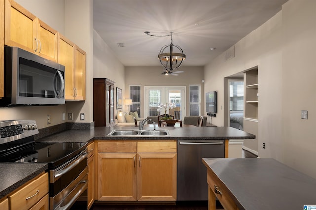 kitchen featuring kitchen peninsula, ceiling fan with notable chandelier, hanging light fixtures, sink, and appliances with stainless steel finishes