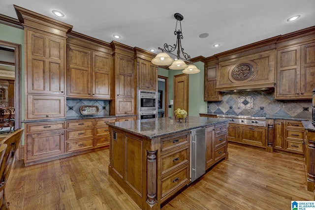 kitchen with appliances with stainless steel finishes, decorative light fixtures, a center island, and dark stone countertops