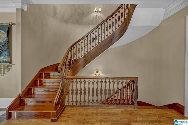 staircase featuring wood-type flooring and ornamental molding