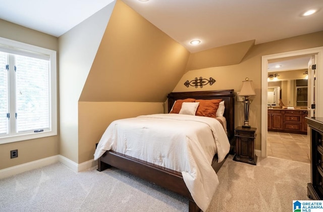 carpeted bedroom featuring ensuite bathroom and vaulted ceiling