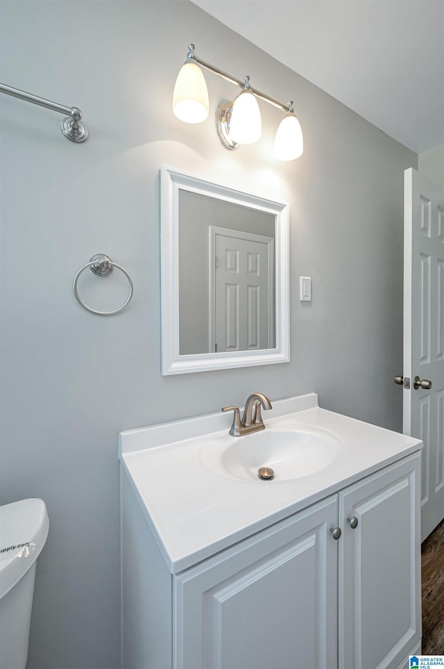 bathroom with hardwood / wood-style floors, vanity, and toilet