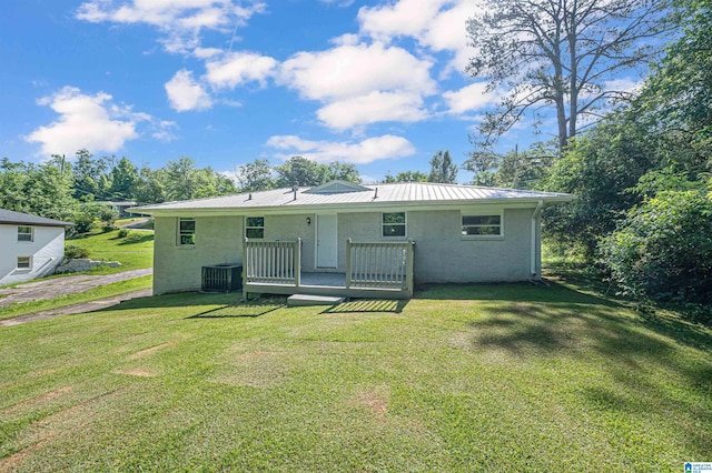 rear view of property with a lawn, central air condition unit, and a wooden deck