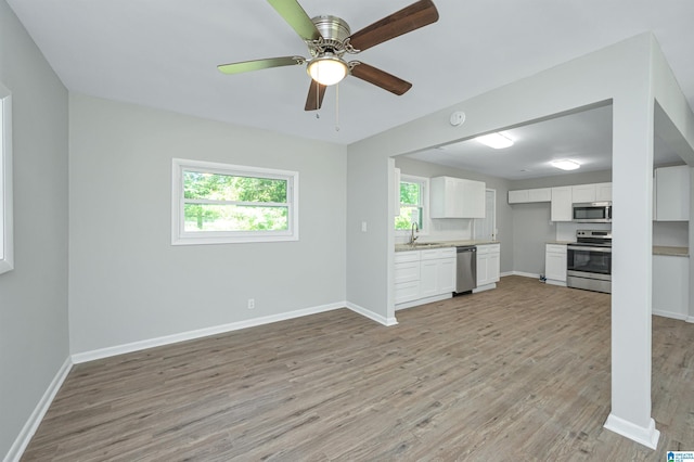 unfurnished living room with light wood-type flooring, ceiling fan, and sink