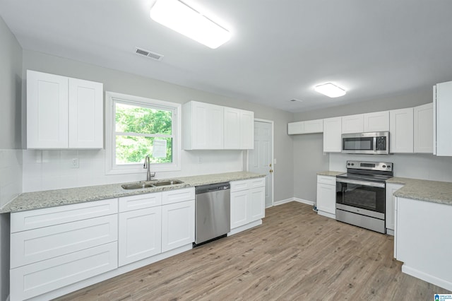 kitchen featuring light stone countertops, appliances with stainless steel finishes, light wood-type flooring, sink, and white cabinets