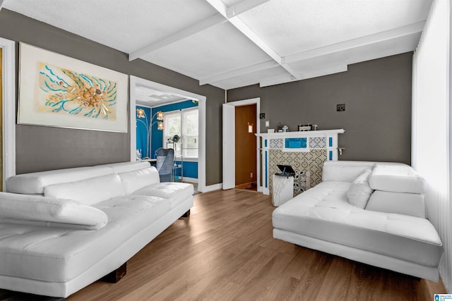 living room featuring beamed ceiling, hardwood / wood-style floors, coffered ceiling, and a tiled fireplace