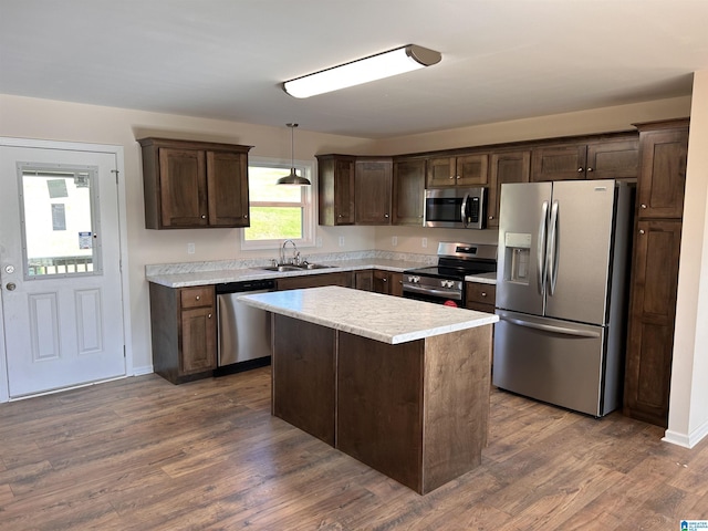 kitchen with a center island, sink, appliances with stainless steel finishes, decorative light fixtures, and dark hardwood / wood-style flooring