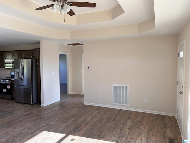 kitchen with appliances with stainless steel finishes, dark hardwood / wood-style flooring, dark brown cabinetry, a raised ceiling, and ceiling fan