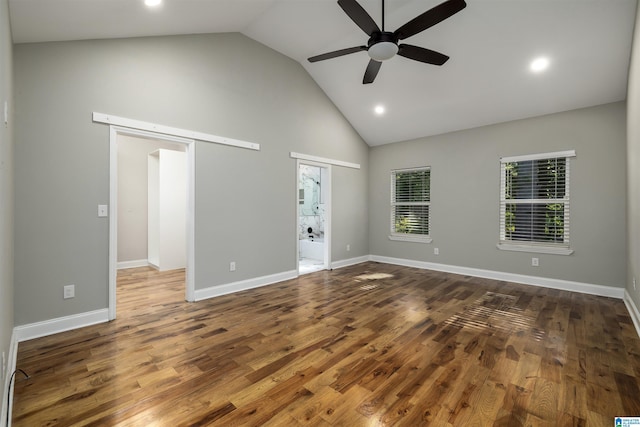 empty room featuring dark hardwood / wood-style floors, vaulted ceiling, and a barn door