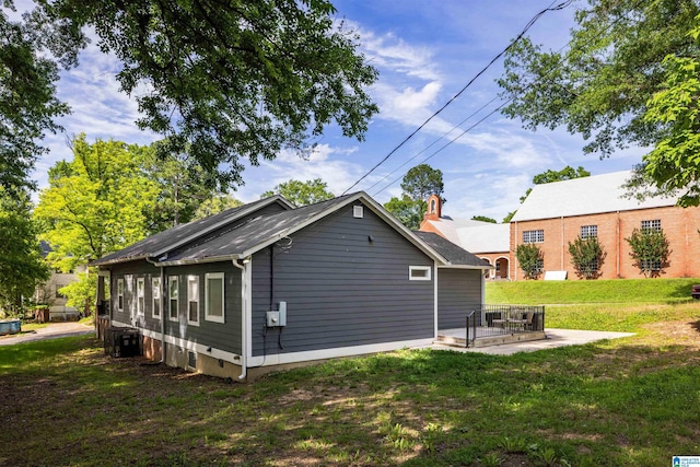 view of side of property featuring central AC unit and a lawn