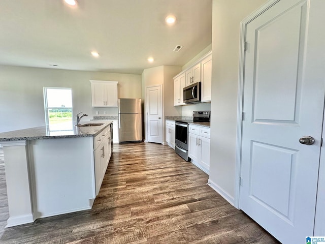 kitchen with sink, white cabinetry, stainless steel appliances, and an island with sink