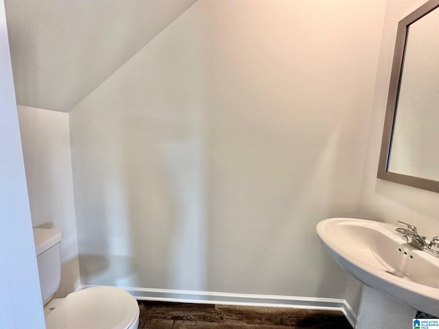 bathroom featuring hardwood / wood-style floors, toilet, sink, and vaulted ceiling