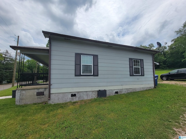 view of side of property featuring crawl space, covered porch, and a lawn