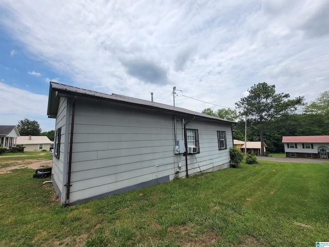 view of side of home featuring cooling unit, metal roof, and a lawn