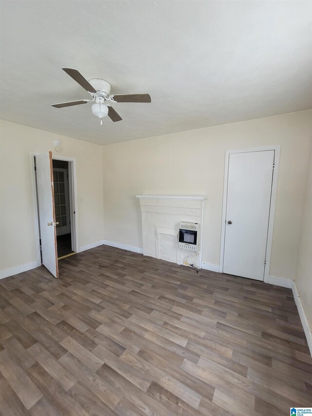 interior space with a textured ceiling, ceiling fan, a fireplace, and dark wood-type flooring