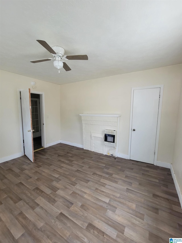 unfurnished living room featuring baseboards, a brick fireplace, wood finished floors, and heating unit