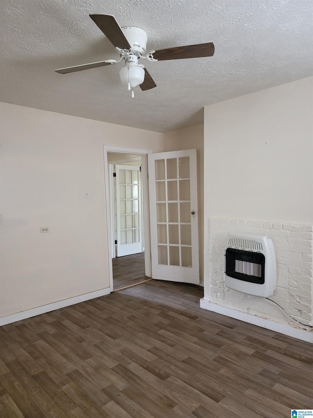 unfurnished living room with heating unit, a ceiling fan, a brick fireplace, a textured ceiling, and wood finished floors