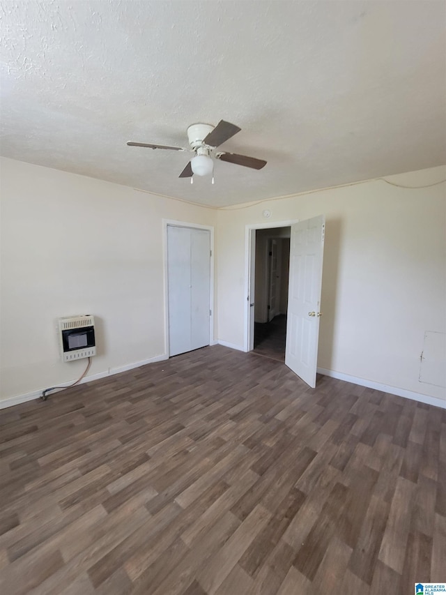 unfurnished room with heating unit, a textured ceiling, baseboards, and wood finished floors