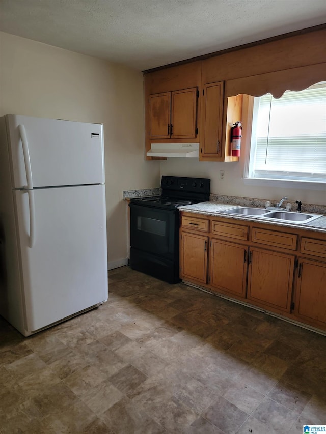 kitchen featuring black electric range, brown cabinetry, freestanding refrigerator, a sink, and under cabinet range hood