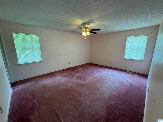 empty room featuring carpet, ceiling fan, a healthy amount of sunlight, and a textured ceiling