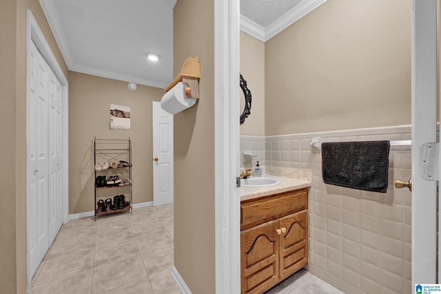 bathroom featuring tile patterned flooring, vanity, crown molding, and tile walls