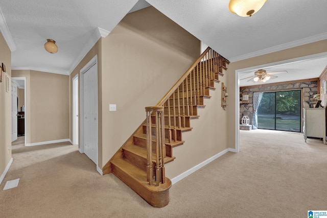 stairway with a textured ceiling, carpet floors, ceiling fan, and crown molding