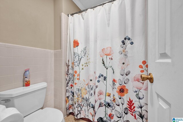 bathroom featuring curtained shower, tile walls, and toilet