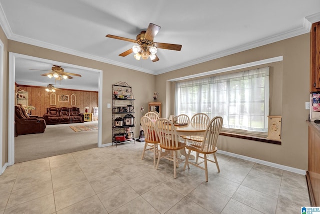 dining space featuring light colored carpet, ceiling fan, ornamental molding, and wood walls