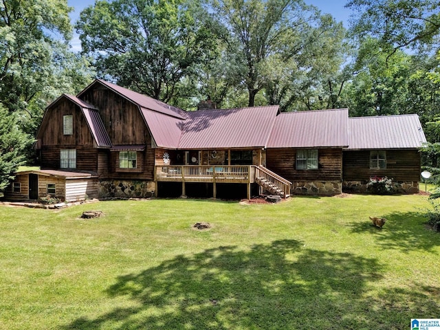 rear view of house with a lawn, a fire pit, and a deck