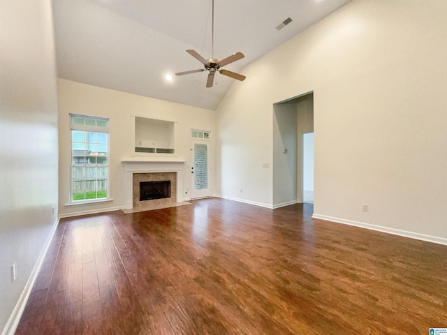 unfurnished living room featuring a tiled fireplace, ceiling fan, high vaulted ceiling, and dark wood-type flooring