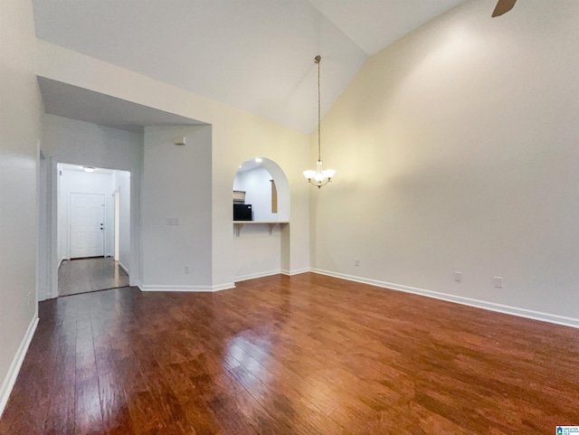 unfurnished living room with dark hardwood / wood-style floors, lofted ceiling, and a notable chandelier