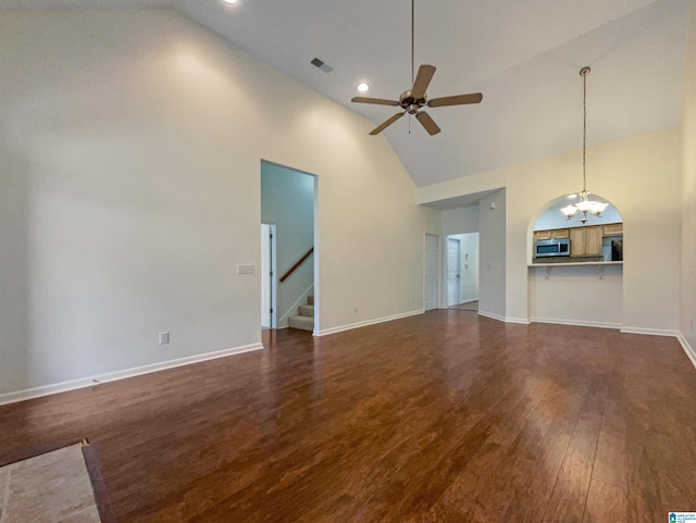 unfurnished living room with dark hardwood / wood-style flooring, high vaulted ceiling, and ceiling fan with notable chandelier