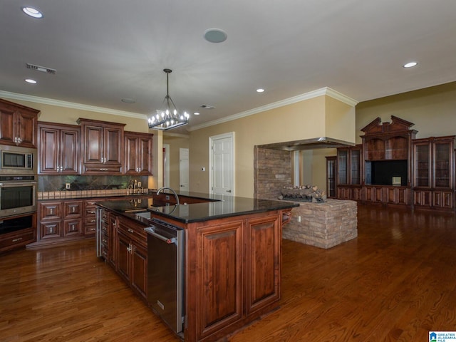 kitchen with tasteful backsplash, stainless steel appliances, dark wood-type flooring, sink, and a kitchen island with sink