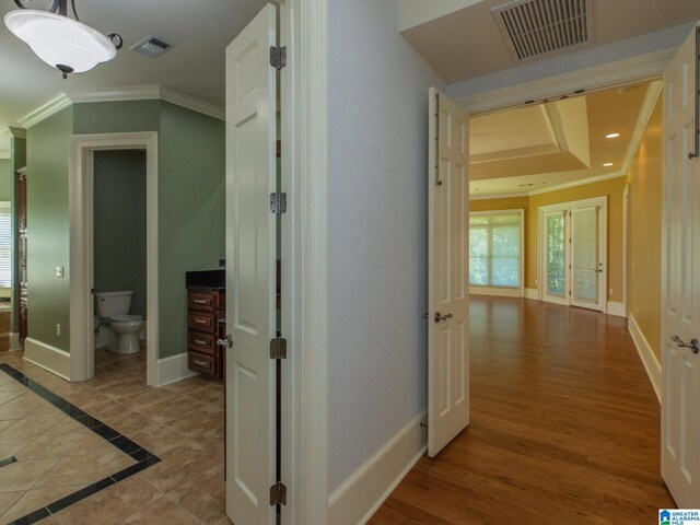 hallway featuring a tray ceiling, crown molding, hardwood / wood-style flooring, and french doors