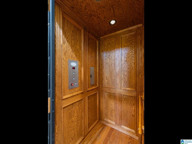 room details featuring wood walls, hardwood / wood-style floors, and elevator