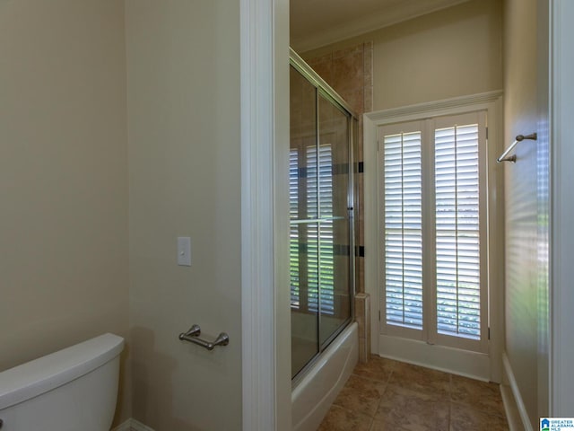 bathroom with tile floors, shower / bath combination with glass door, crown molding, and toilet