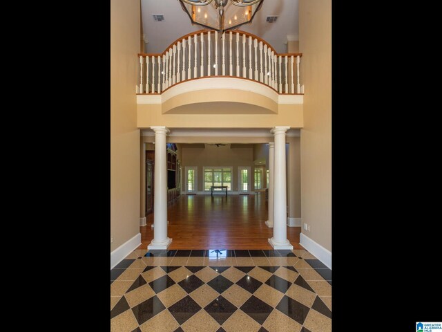 tiled foyer with a chandelier, ornate columns, and a high ceiling