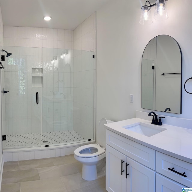 bathroom with tile patterned flooring, vanity, a shower with shower door, and toilet