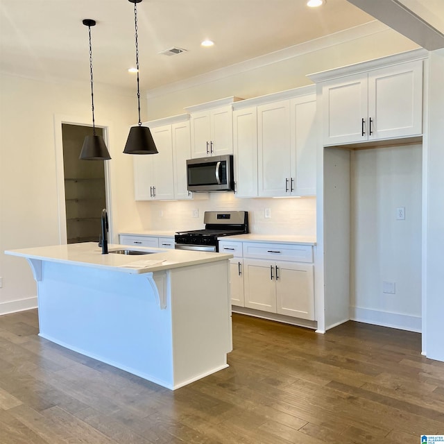 kitchen featuring appliances with stainless steel finishes, dark hardwood / wood-style floors, an island with sink, pendant lighting, and white cabinets