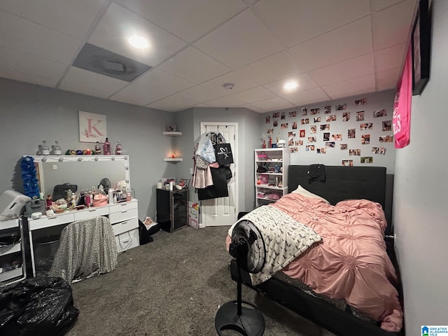 carpeted bedroom featuring a drop ceiling