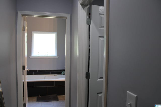 bathroom with tile patterned flooring and tiled bath