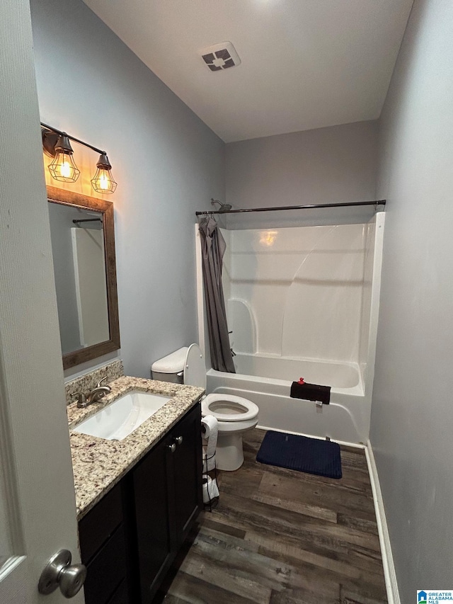 bathroom with visible vents, toilet, wood finished floors, vanity, and shower / bathtub combination with curtain