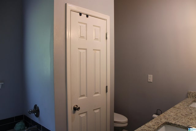 bathroom with toilet and dual bowl vanity