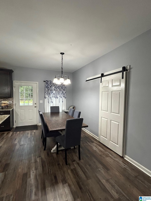 dining space with dark hardwood / wood-style floors, a barn door, and a chandelier