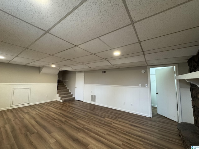 finished basement with wainscoting, visible vents, stairway, and wood finished floors