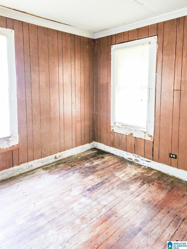 unfurnished room with hardwood / wood-style floors, crown molding, and wood walls