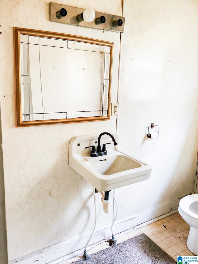 bathroom with toilet, tile patterned flooring, and sink