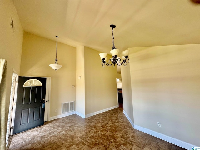 tiled entryway with high vaulted ceiling and an inviting chandelier