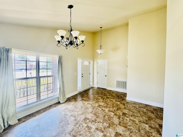 foyer featuring visible vents, baseboards, an inviting chandelier, and a towering ceiling