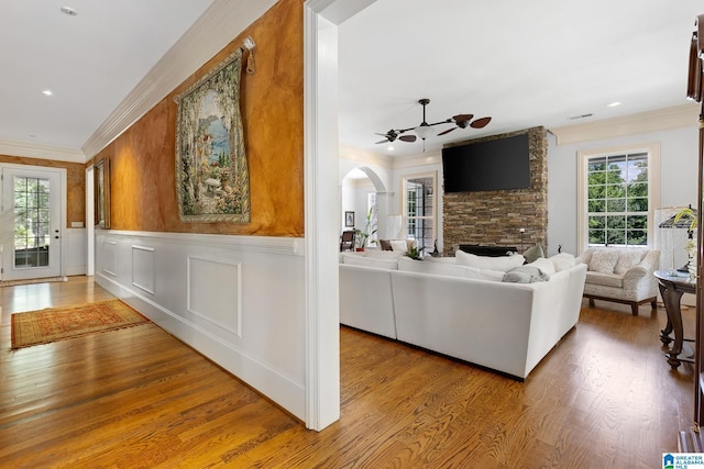 living room with wood-type flooring, plenty of natural light, a stone fireplace, and ceiling fan