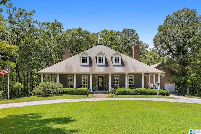 new england style home featuring a garage, a front yard, and a porch